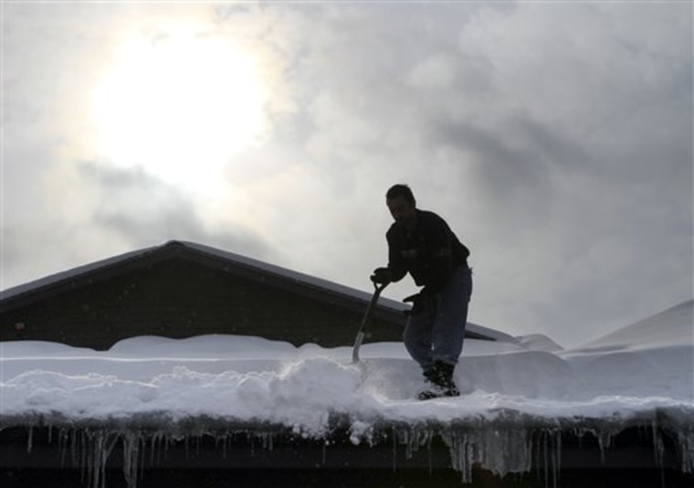 Anesti Karathanasis shovels snow off the roof of his restaurant in Concord, N.H., on Friday.